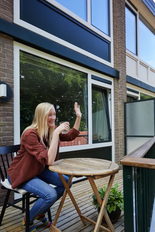 Inwoner zit op haar balkon en zwaait