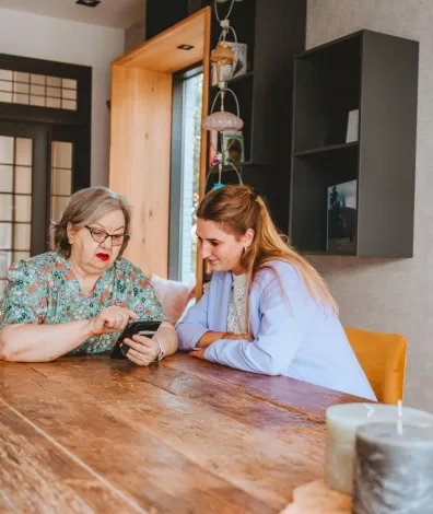 2 vrouwen aan tafel kijken op een telefoon