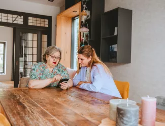 2 vrouwen aan tafel kijken op een telefoon