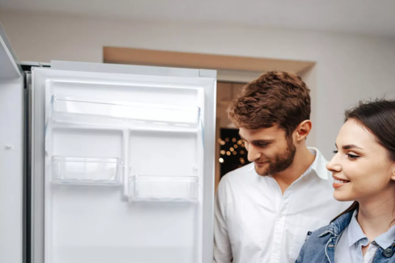 man en vrouwen zoeken koelkast uit in winkel